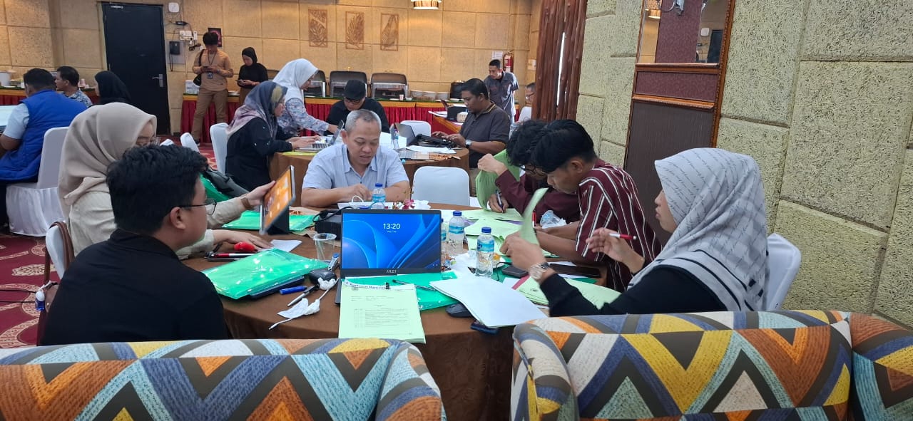 Peserta pelatihan jurnalistik berdiskusi di meja kerja dengan dokumen dan laptop